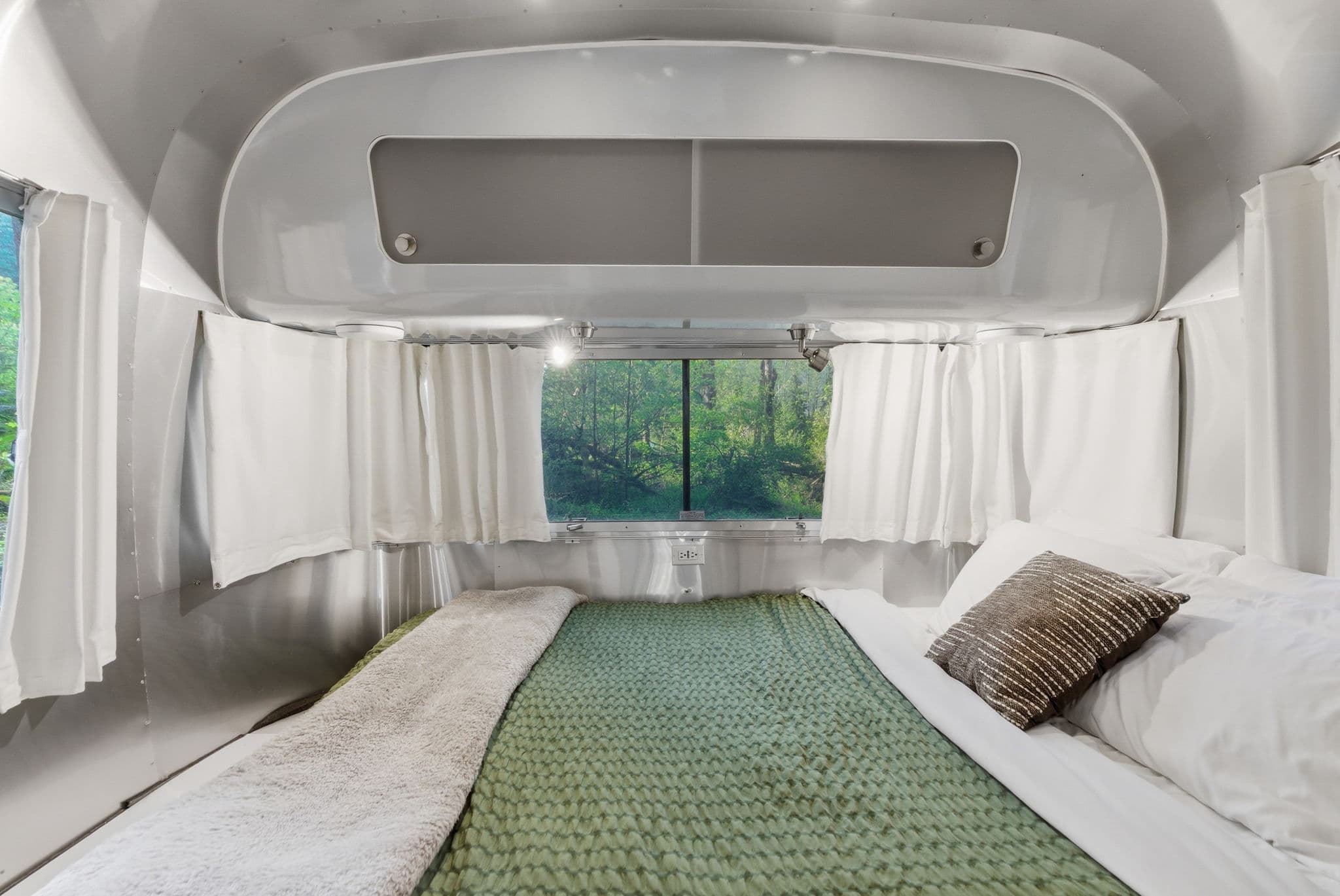 Airstream rear sleeping nook with forest view