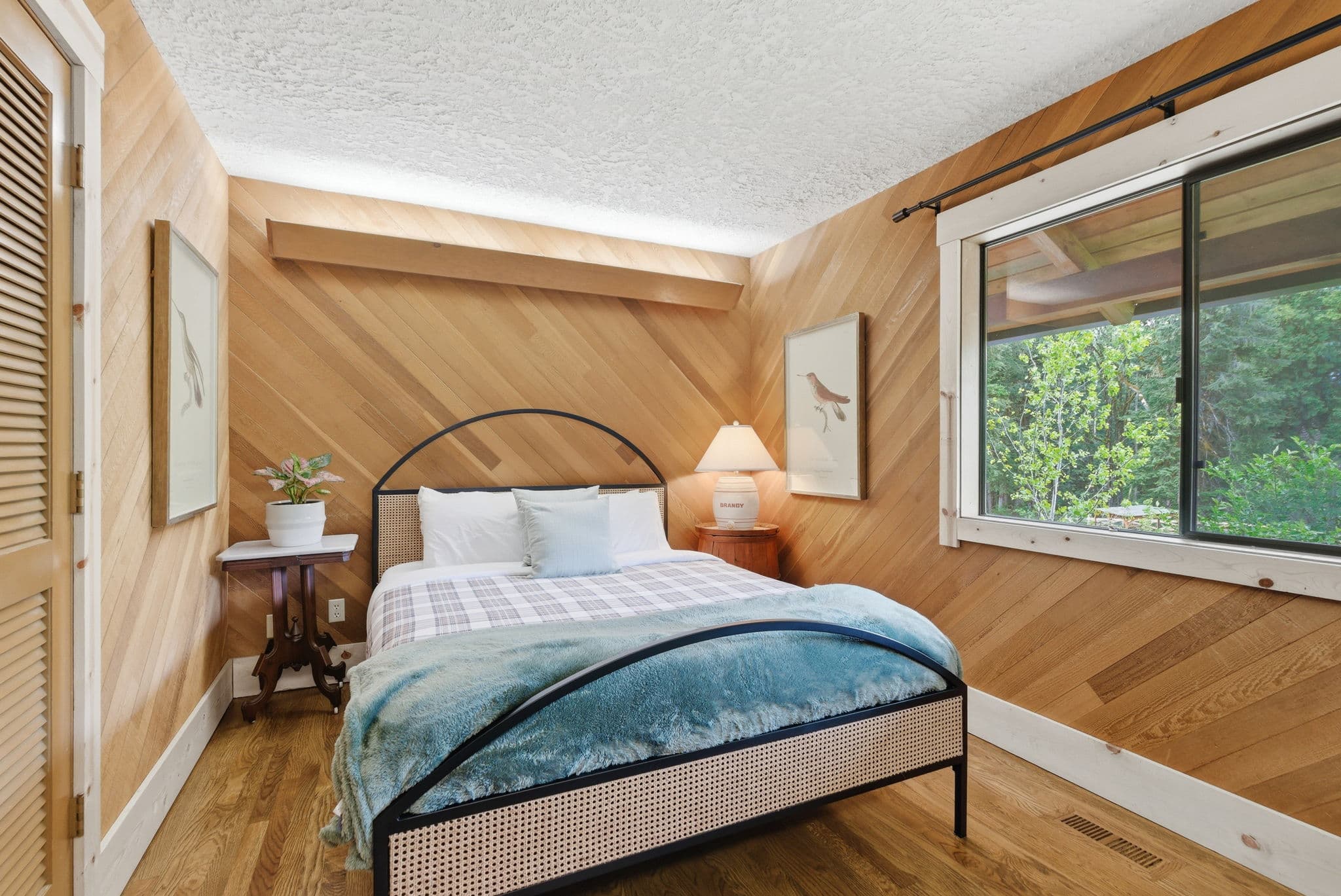 Bedroom with cedar herringbone wood paneling and a queen bed with plaid bedding