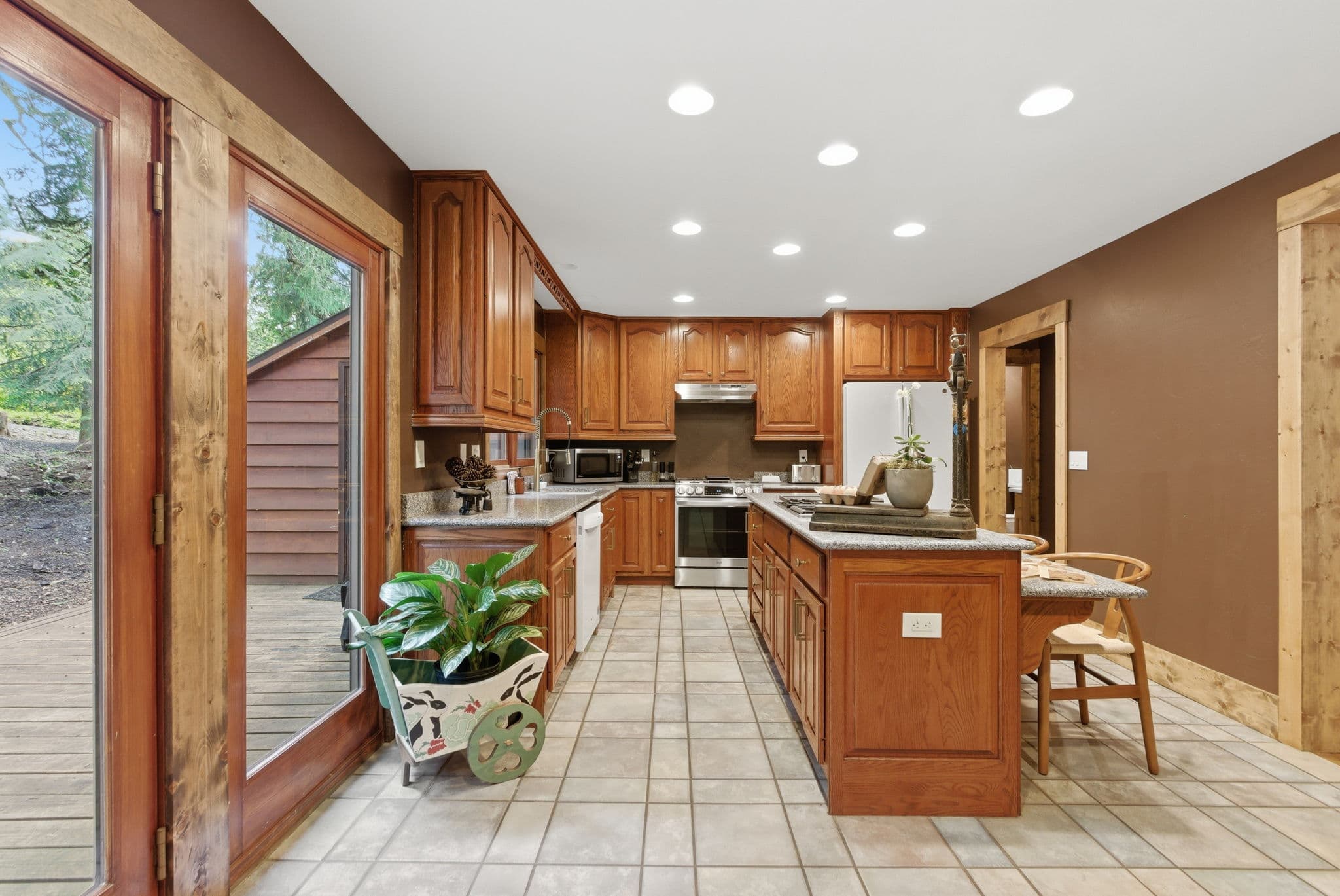 Full chef's kitchen with oak cabinets, granite island, and French doors to the deck
