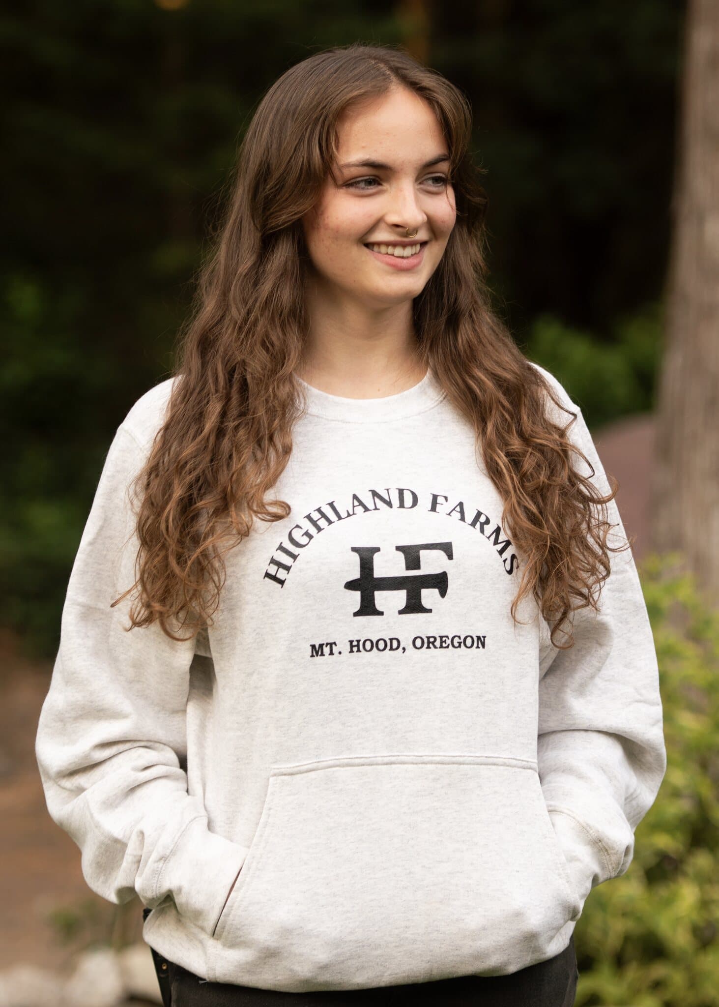 Model wearing a heather gray Farm Crewneck with black Highland Farms chest print, outdoors