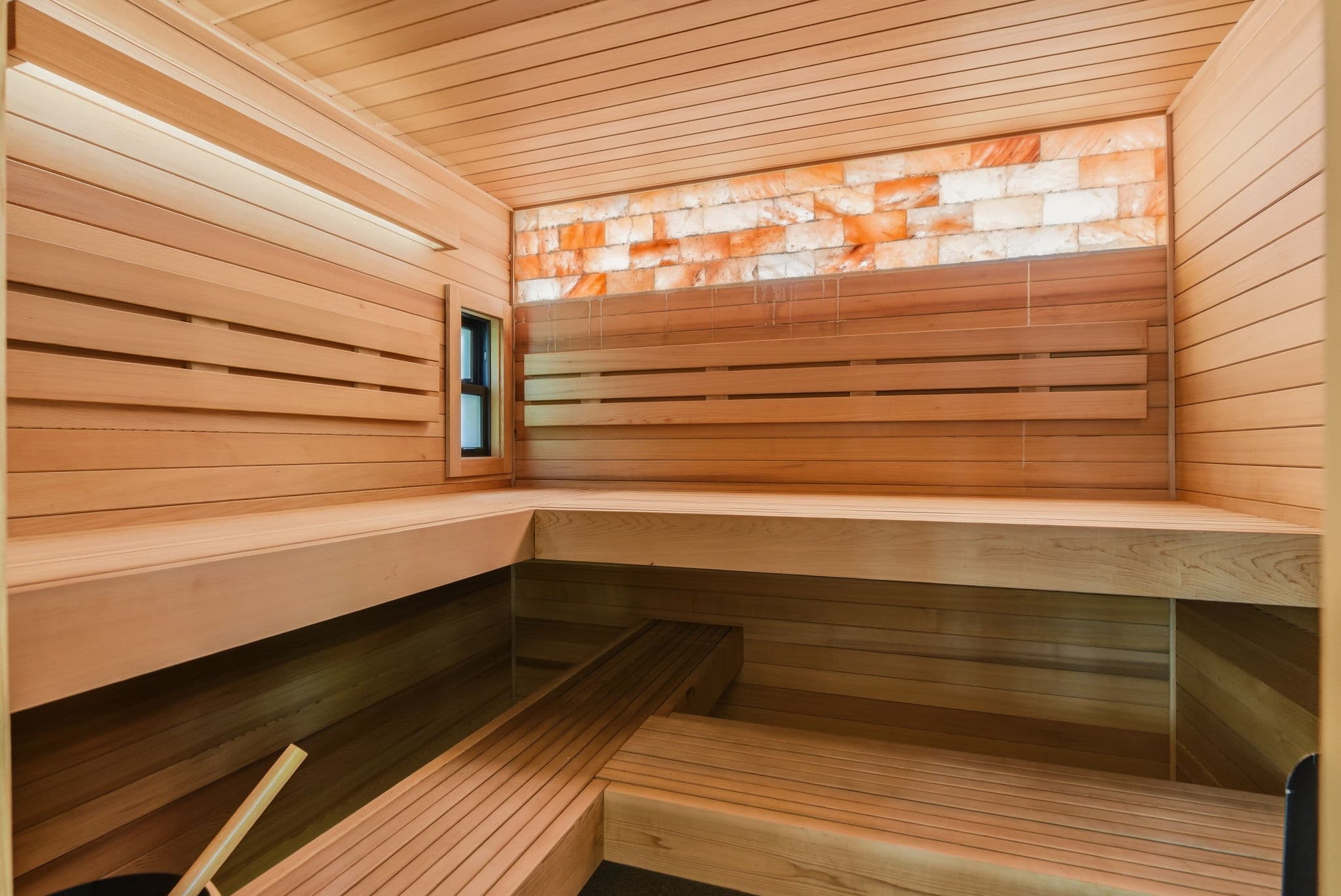 Inside the cedar sauna: tiered benches and a glowing salt-brick panel