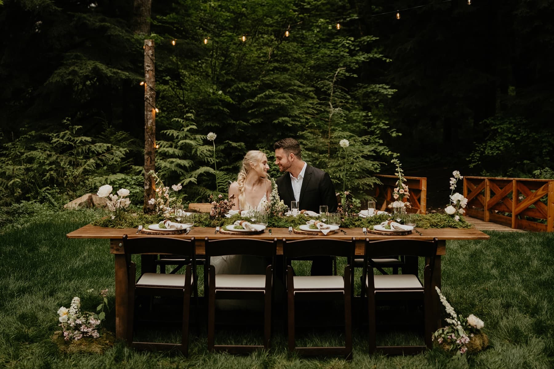 Couple at sweetheart table with string lights