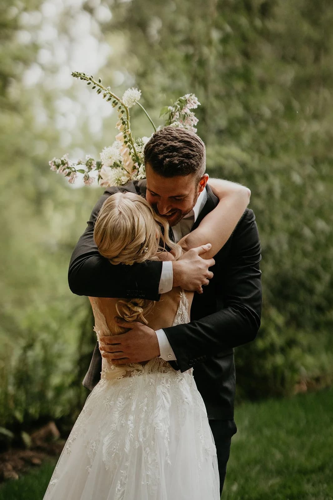 Two people in wedding clothes embrace on the lawn